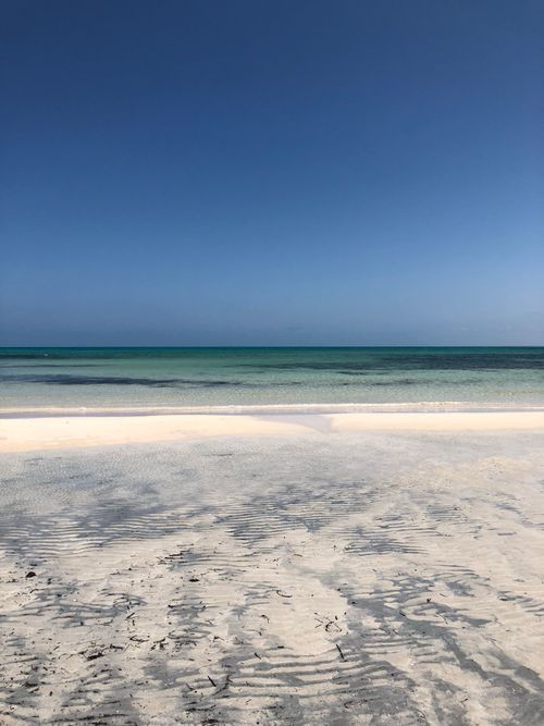 Free Serene beach scene with clear skies, turquoise water, and pristine sand. Perfect for relaxation imagery. Stock Photo