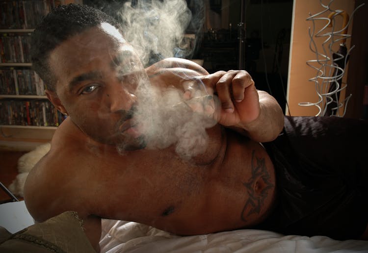 A Man In Bed Smoking A Cigarette