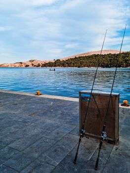 Serene view of two fishing rods by a Greek seaside, perfect for capturing tranquility.