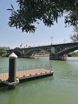 Beautiful warm day capturing the historic Triana Bridge over the Guadalquivir River in Seville.