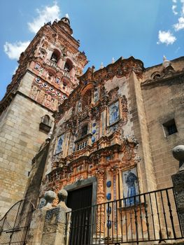 Gothic facade of San Bartolome Church under a clear blue sky in Jerez de los Caballeros, Spain.