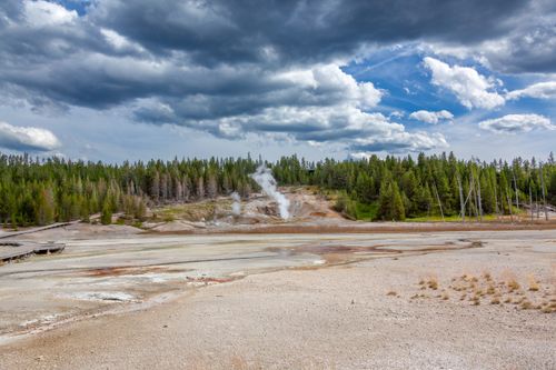 Free Scenic view of a geyser under a dramatic sky in Yellowstone National Park. Stock Photo