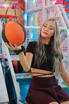 Young woman in crop top holding basketball at an arcade, captured indoors.