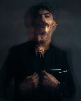 Blurry artistic portrait of a bearded man wearing a black blazer with a double exposure effect.