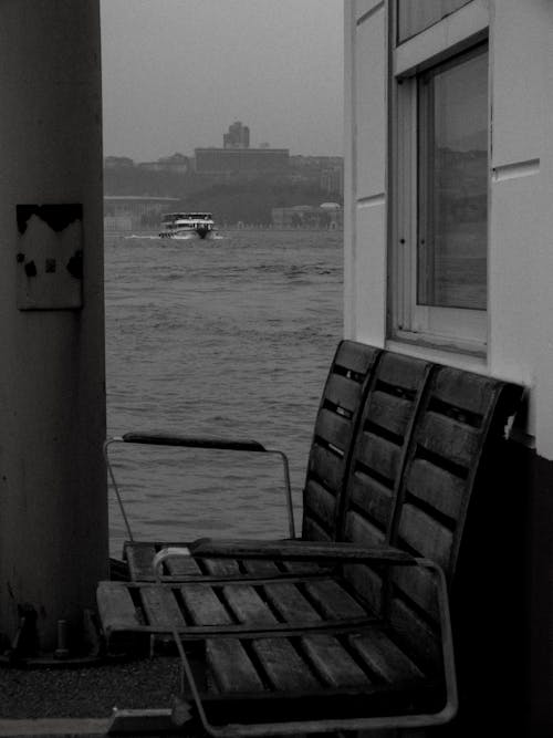 Black and White Shot of Benches by a Pole with a View on the Sea