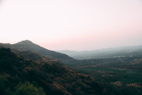 Free A calming aerial view of misty hills and a distant valley at sunrise, with soft lighting and natural tones. Stock Photo