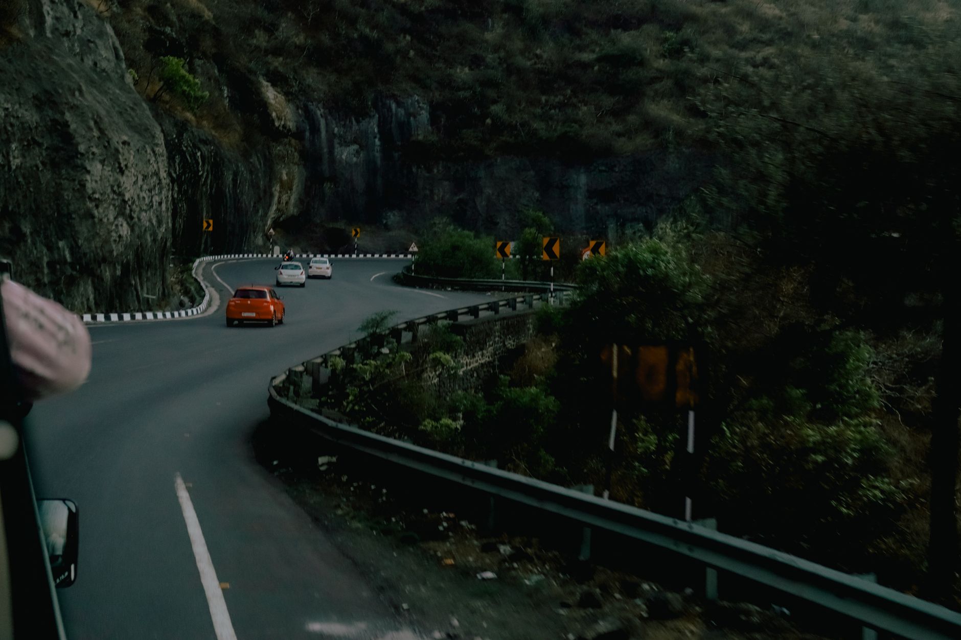 Scenic mountain road with cars navigating sharp turns, vibrant nature surrounding.