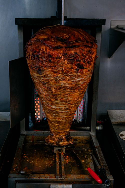 Free Closeup of a richly seasoned shawarma meat stack rotating on a vertical grill. Traditional street food. Stock Photo