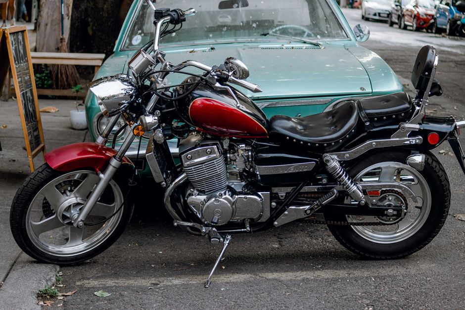 A sleek vintage motorcycle parked on a city street, adjacent to a classic car.