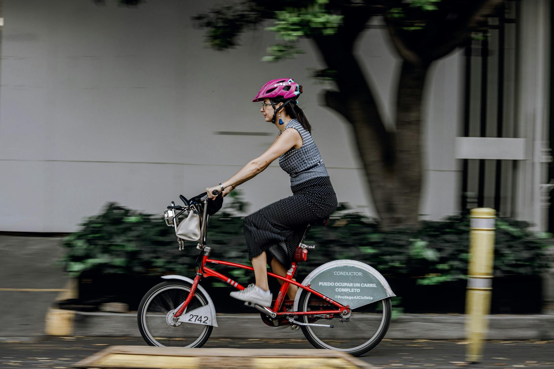 Active woman riding a bicycle outdoors in a city wearing a safety helmet.