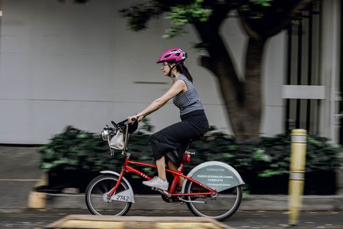 Free Active woman riding a bicycle outdoors in a city wearing a safety helmet. Stock Photo