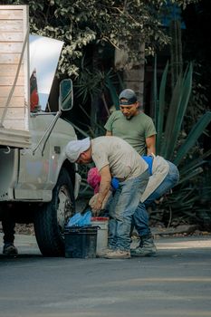 Group of men repairing a truck tire on a sunlit street with tools and teamwork.