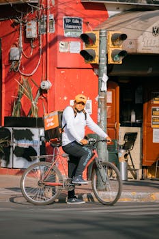 Urban street scene featuring a delivery person on a bicycle with a vibrant red building backdrop.