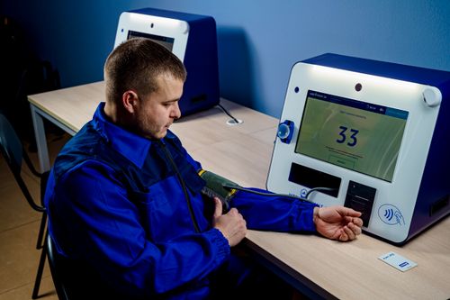 Free A man uses a modern machine to measure his blood pressure indoors. Stock Photo
