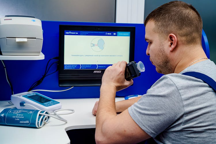 A Man Measuring His Alcohol Blood Content Using A Breathalyzer