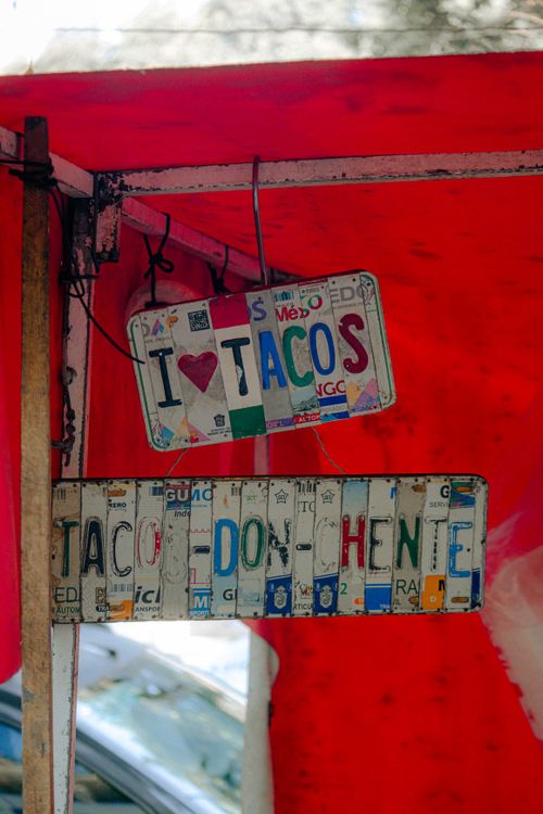 Free Colorful metal signs at a taco stand with vibrant red canopy. Stock Photo