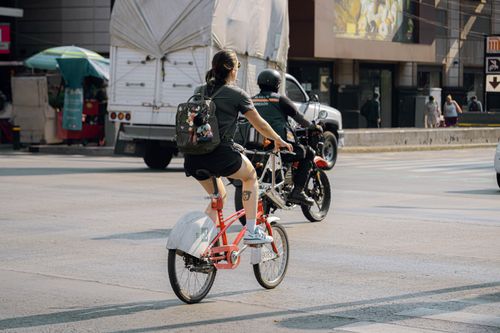Free Woman biking through city streets, blending lifestyle and urban transit. Stock Photo