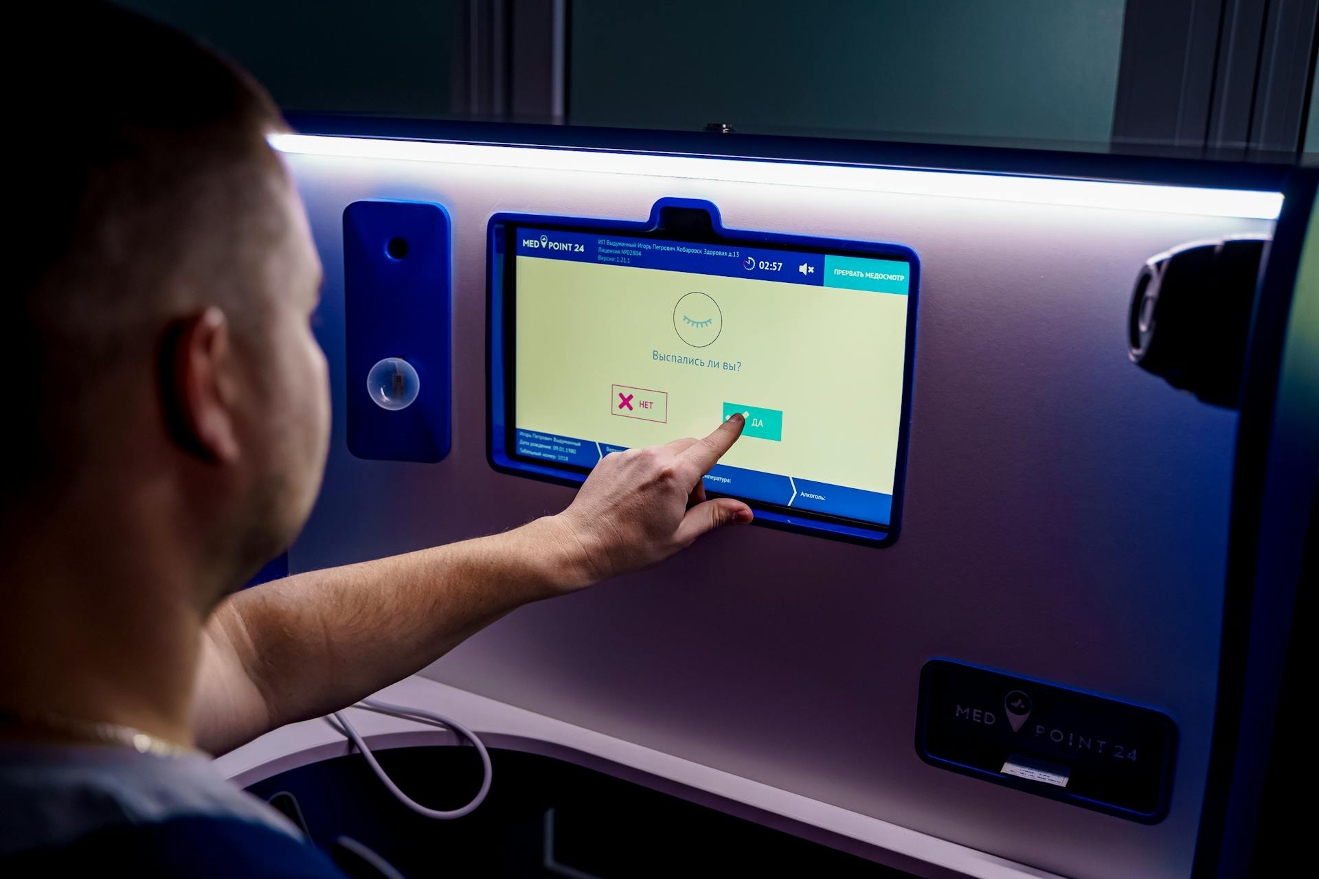 A man interacts with a touchscreen kiosk for telemedicine services, emphasizing modern healthcare technology.