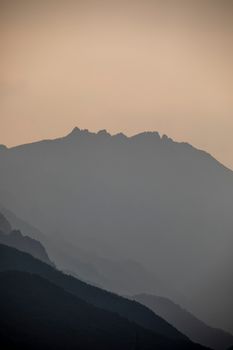 Foggy mountain peaks silhouette at sunrise in Yangyang, South Korea, creating a serene and moody landscape.