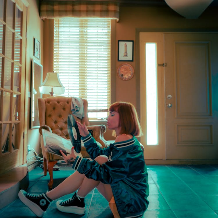 Woman Holding A Phonograph Record While Sitting On Floor