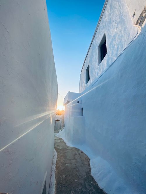 Free Stunning view of a narrow whitewashed alley in Santorini during sunset with sunbeam effect. Stock Photo