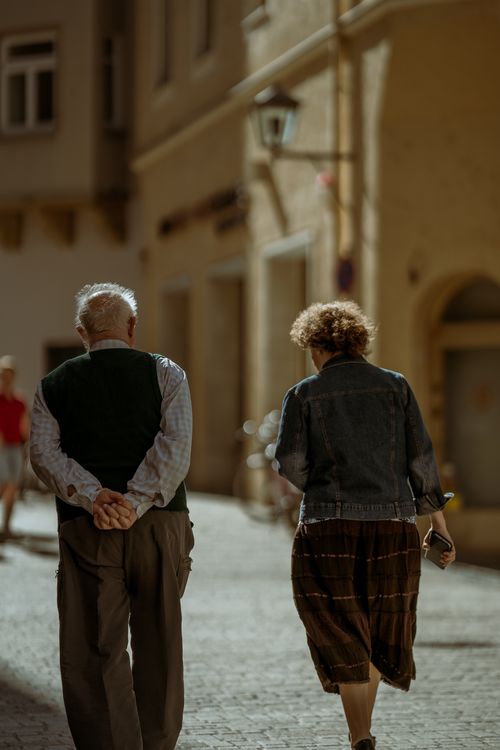 Free Senior couple walking together down a sunlit street with a sense of companionship. Stock Photo