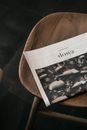 A close-up shot of a magazine resting on a wooden chair, creating a cozy and minimalist atmosphere.