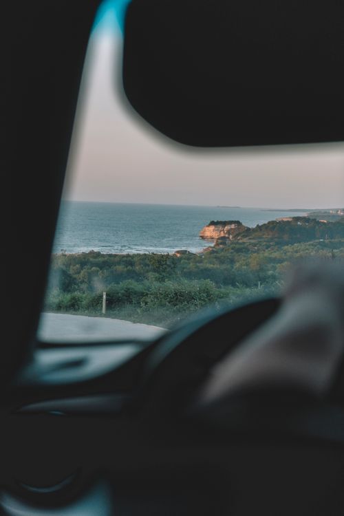 Free A blurred view through a car window of a coastal landscape with a sea view at dusk. Stock Photo