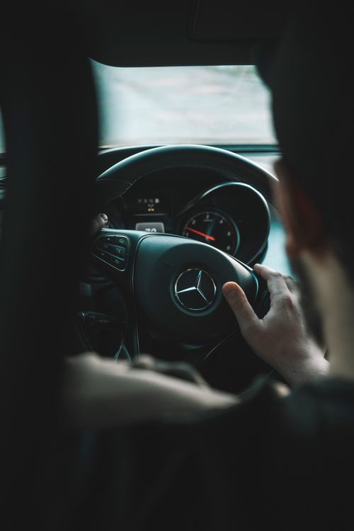 Free View from the backseat of a man driving a Mercedes Benz, focused on the steering wheel. Stock Photo