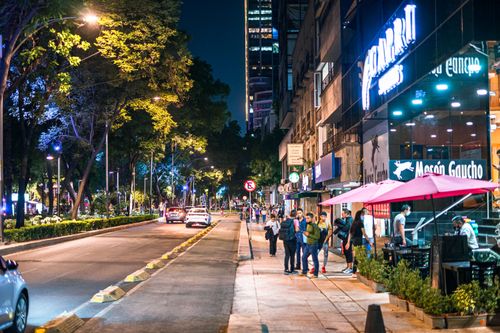 Free Lively street scene in Mexico City featuring people, restaurants, and illuminated storefronts at night. Stock Photo