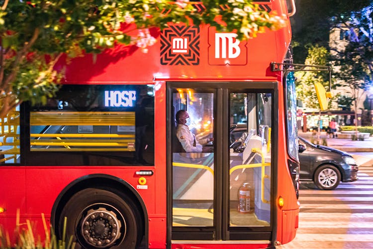 A Man Wearing Face Mask Driving A Red Bus During The New Normal State