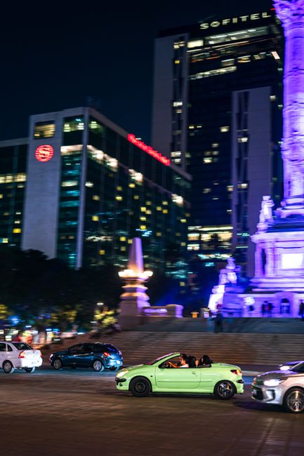 Vibrant city night scene at Angel of Independence, Mexico City with colorful cars and illuminated monuments.