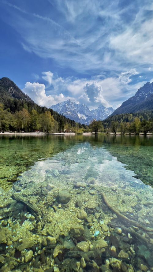 Free Crystal clear lake reflecting mountains and sky in Slovenia's stunning nature. Stock Photo