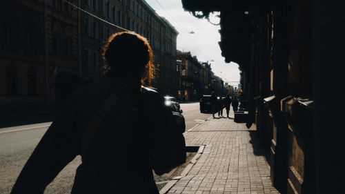 Free Silhouette of a person walking down a sunlit street in Saint Petersburg, Russia. Stock Photo