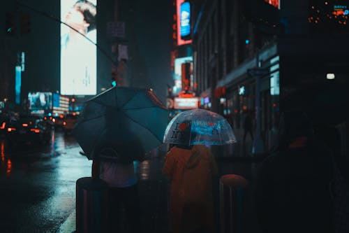 Backview of People using an Umbrella while Walking on Street