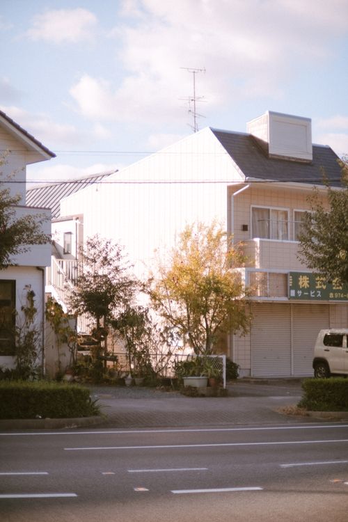 Free Quiet suburban street with small residential buildings and light traffic under daylight. Stock Photo