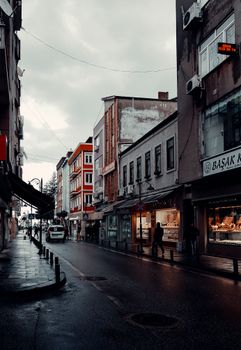 A moody, wet urban street with shops and old buildings. A perfect backdrop for street photography.