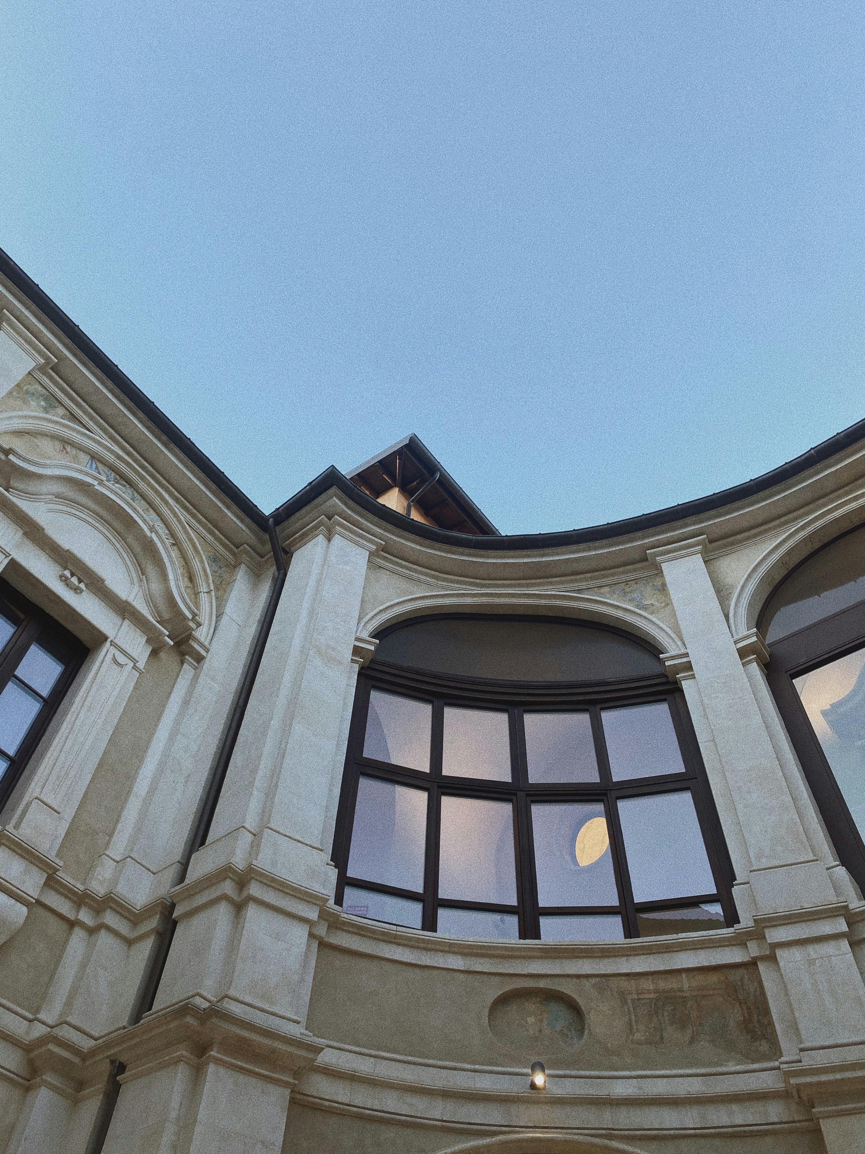 Architectural low angle view of a classic building with arched windows against a clear blue sky.