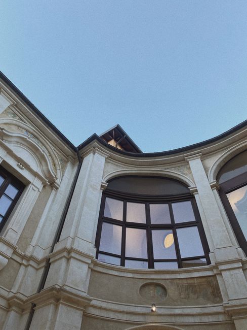 Architectural low angle view of a classic building with arched windows against a clear blue sky.