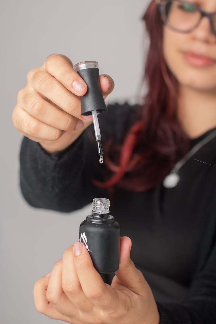 A Woman Holding A Nail Polish Bottle And Brush