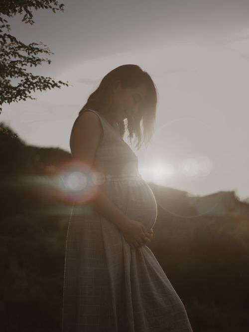 Free Silhouette of a pregnant woman in a dress during sunset, capturing a serene moment. Stock Photo