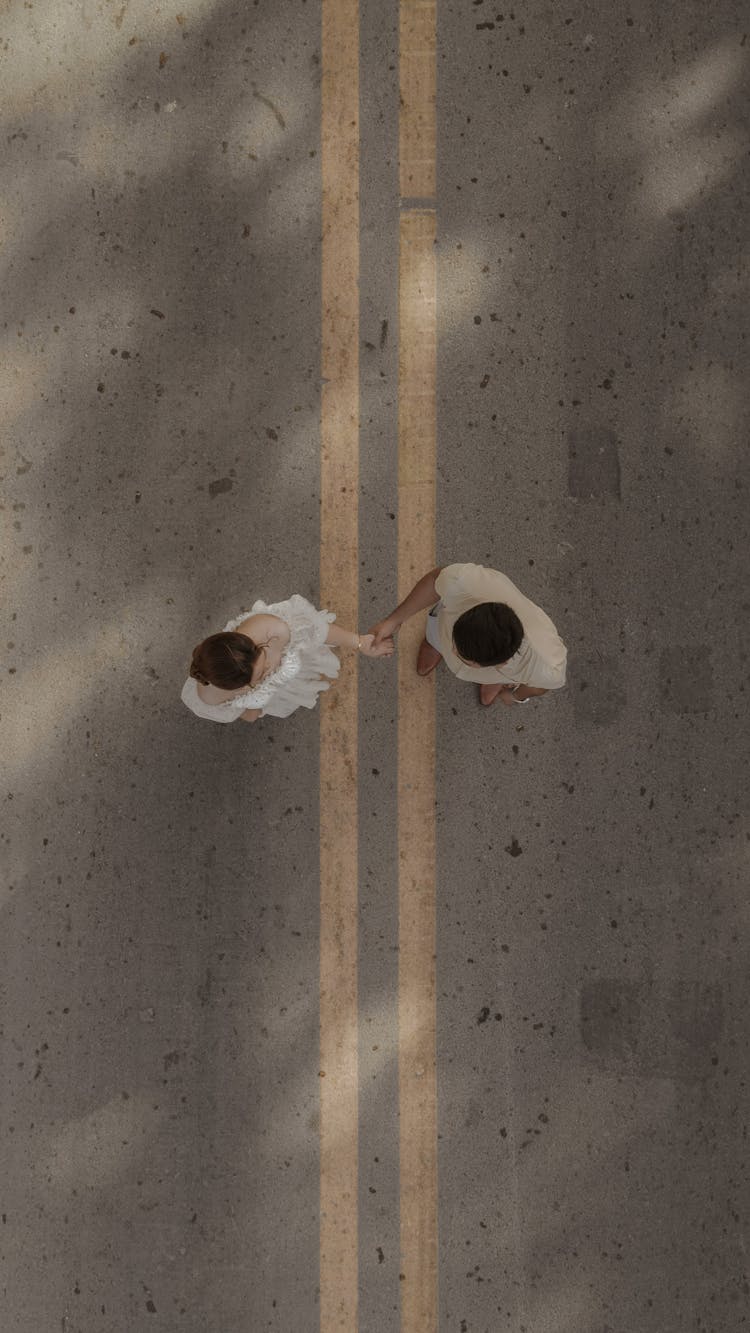 Aerial Shot Of Couple Dressed In White Holding Hands