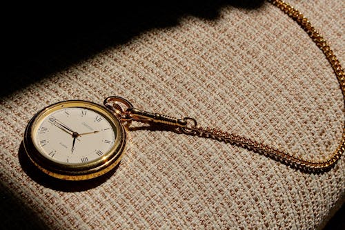 Free A Gold Pocket Watch on a Woven Fabric Stock Photo