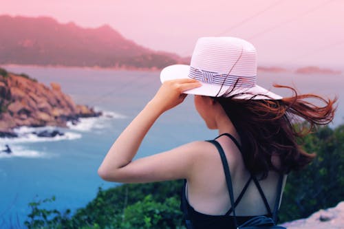 Wman Holding Wricker Shade Hat on Ocean View