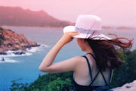 一位戴着太阳帽的女士欣赏着充满活力的海岸景色，捕捉到了宁静的假期瞬间