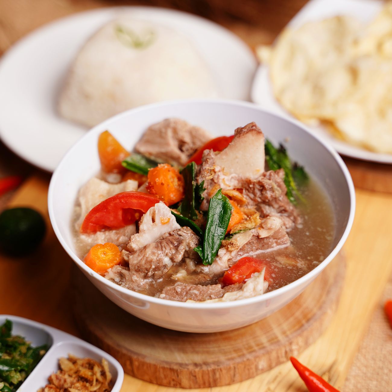 hearty meat soup served with rice and crackers on a wooden table