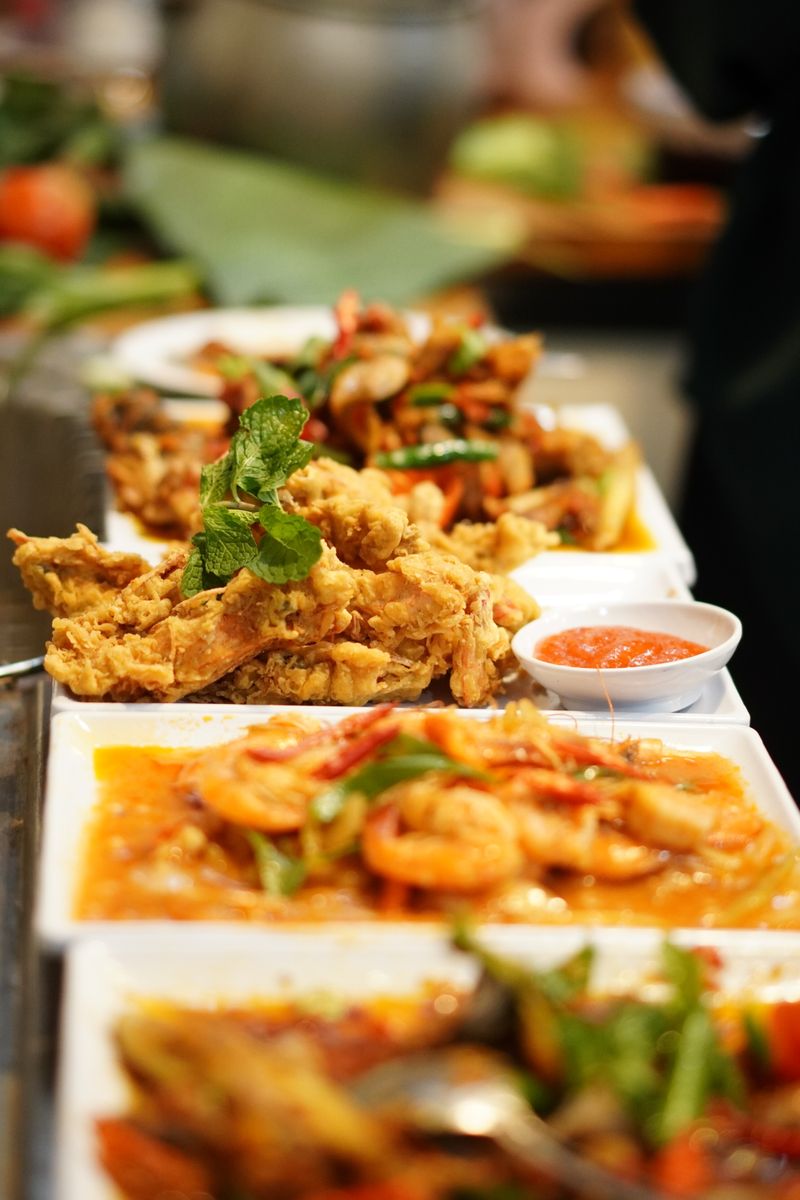 A variety of Indonesian dishes featuring fried chicken and shrimp with vibrant garnishes.