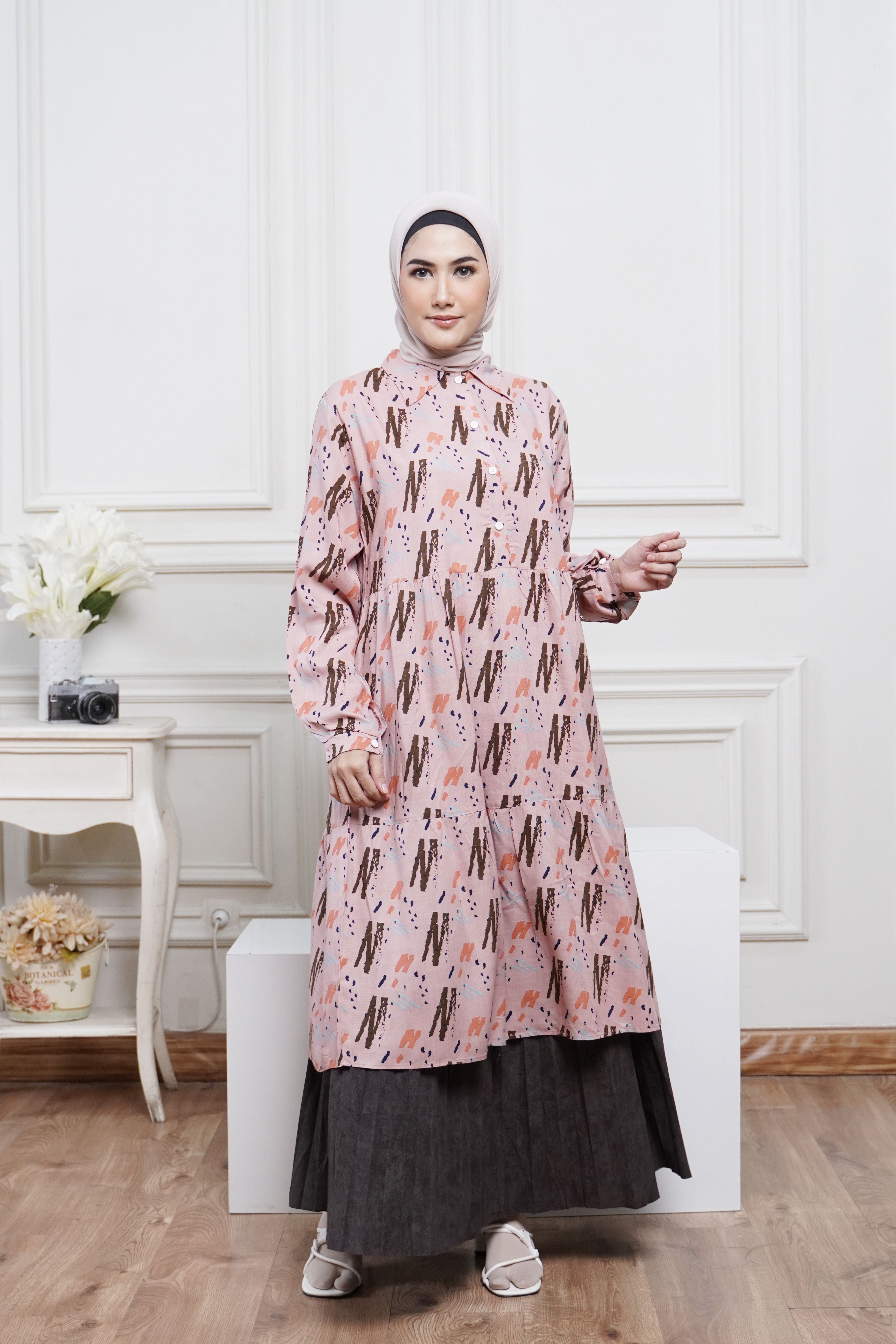 Stylish Muslim woman in a modern printed dress posing gracefully indoors.