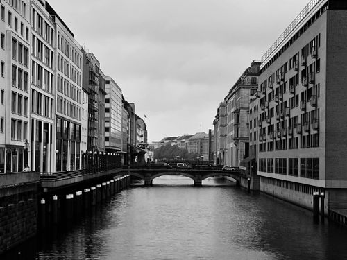Free Grayscale cityscape featuring a canal, bridge, and modern buildings. Stock Photo