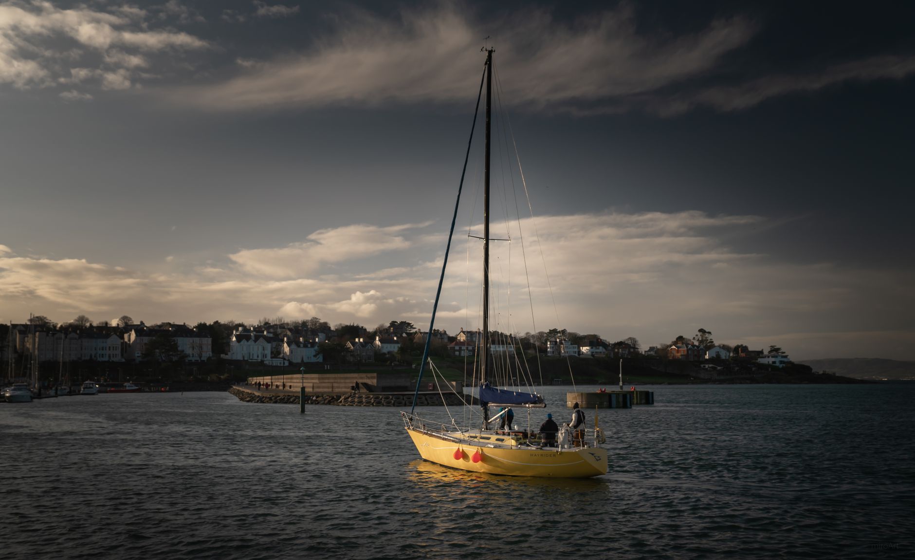 A yellow sailboat cruising under a moody sky near Bangor Harbor, Northern Ireland.